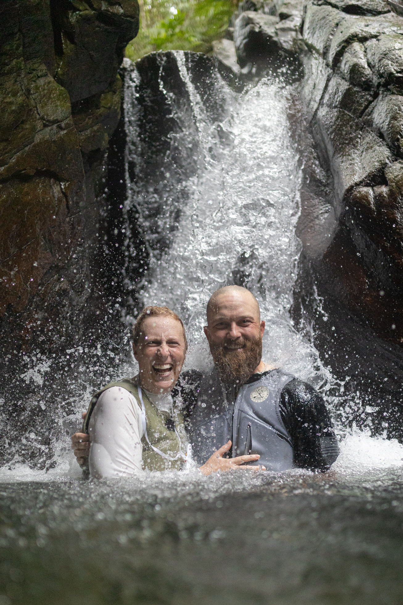 A couple smiling together in front of a waterfall in Yanbaru